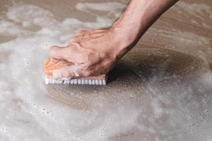 Close-up of person cleaning a floor with a brush
