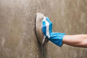 Close-up of a person cleaning a wall with a sponge photo