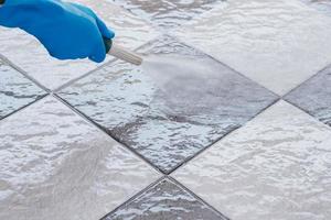 Close-up of a person spraying a tile floor with water photo