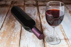 Wine glass and wine bottle on wooden table photo