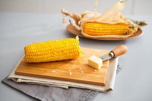 Boiled corn and butter on cutting board. Closeup