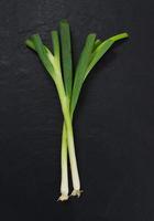 two spring onions on black slate stone photo