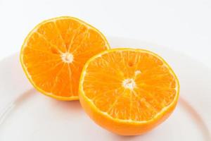 Media fruta naranja sobre fondo blanco, fresca y jugosa