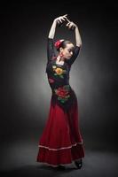 young woman dancing flamenco with castanets on black photo
