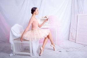 Professional ballet dancer looking in the mirror on pink photo