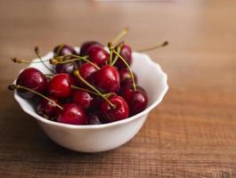 Cherries on wooden table with water drops macro background photo
