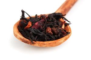 Fruta negra hojas de té secas en cuchara de madera blanco aislado