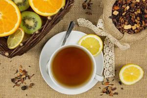 taza de té caliente, hojas de hierbas y frutas maduras foto