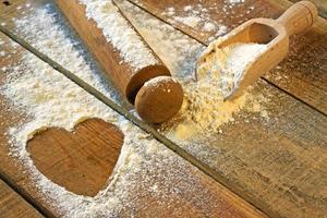 flour, rolling pin and heart with wood background photo