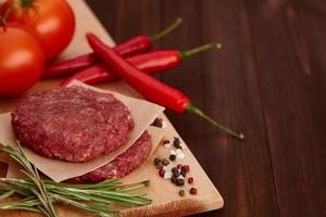 Raw meat for burgers with spices on wooden board photo
