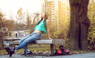 Roller girl drinking water on bench photo
