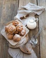 Cinnamon buns with sugar powder on rustic wooden board, jug