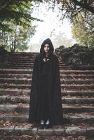 Hermosa mujer vampiro oscura con manto negro y capucha foto