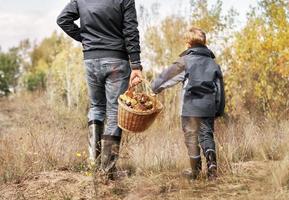 Father and son carry full basket of mushrooms photo