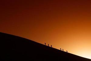 Silhouettes of a team mountain peak. Sport and active lif photo