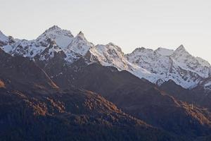 picos de las montañas cubiertas de nieve en la luz del atardecer foto