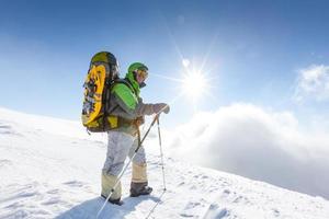 Backpacker man is posing in winter mountains
