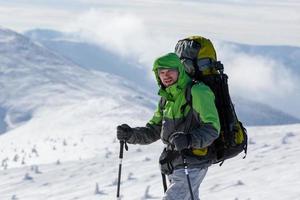 Hombre mochilero caminando en las montañas de invierno en un día soleado foto