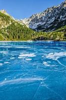 Mountain frozen lake with cracked textured ice photo
