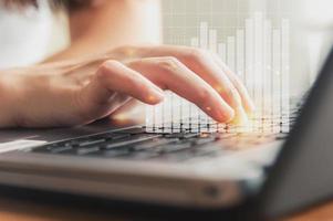 female hand using keyboard with financial graph photo