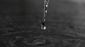 Super slow motion video of water flow hitting dark smooth surface