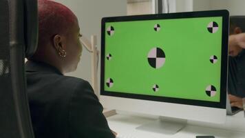 Woman sitting in front of computer monitor with green screen and icons video