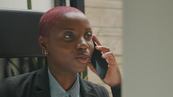 Mujer joven hablando por teléfono inteligente en la oficina en casa video