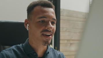 Young man wearing ear phones talking in online meeting
