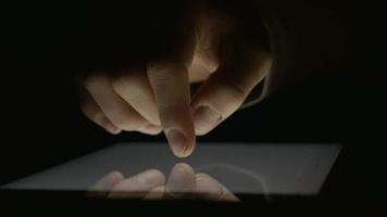 close-up da mão usando o tablet pc no escuro
