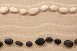 Two rows of white and black stones  on the sand photo