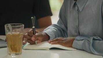 jovem fazendo anotações no escritório com um colega video