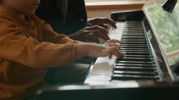Tilt up of mature man teaching grandson piano