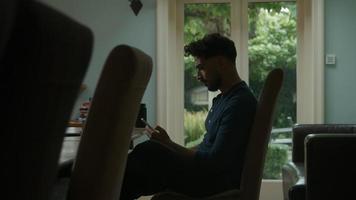 Young man texting on phone working from home video