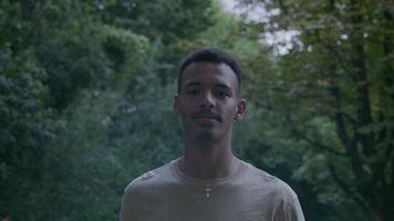 Slow motion of young man walking in park looking at camera