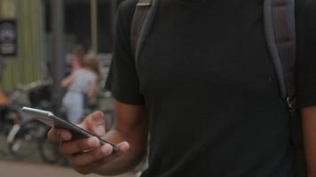 Zeitlupen-Neigung des jungen Mannes unter Verwendung des Smartphones, das Ohrstöpsel trägt video