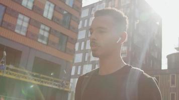 Slow motion of young man walking in city wearing ear pods