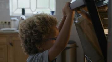 Boy putting homemade cookies in oven video