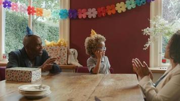 jongen uitblazen van kaarsjes op de taart met familie zingen gelukkige verjaardag video