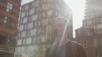 Zeitlupe des jungen Mannes, der im Sonnenlicht der Stadt geht video