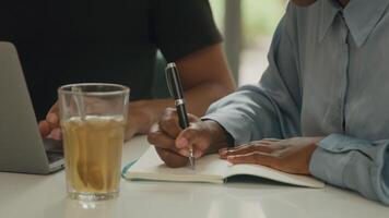 Young woman making notes in office with colleague video