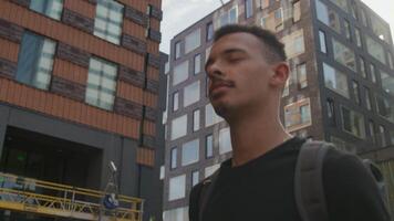 Slow motion of young man walking by city buildings video