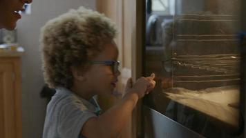 jongen die op zelfgemaakte koekjes wacht om uit de oven te komen