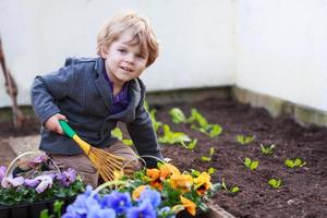 Niñito jardinería y plantar flores en el jardín