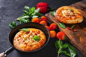 Pizza in a pan and an other one on a wooden tray photo