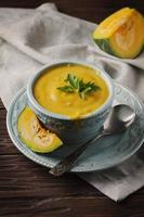 Pumpkin soup with parsley on vintage table photo