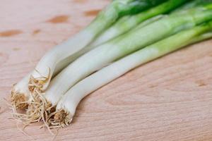 green spring onions on wooden background photo