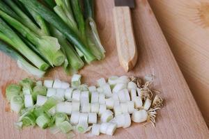 chopped green spring onions on wooden cutting board photo