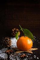 Tangerine on Wooden Boards with snow and fir cone