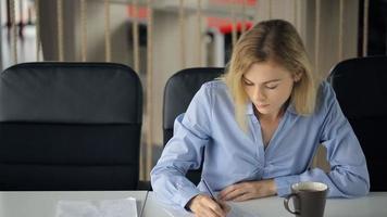 jonge aantrekkelijke blonde vrouw zittend aan een tafel en vragenlijst in te vullen met een potlood video