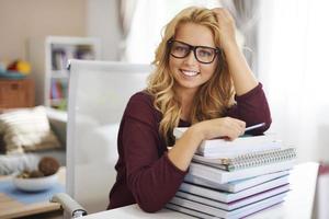 Pretty female student leaning on stack of book photo